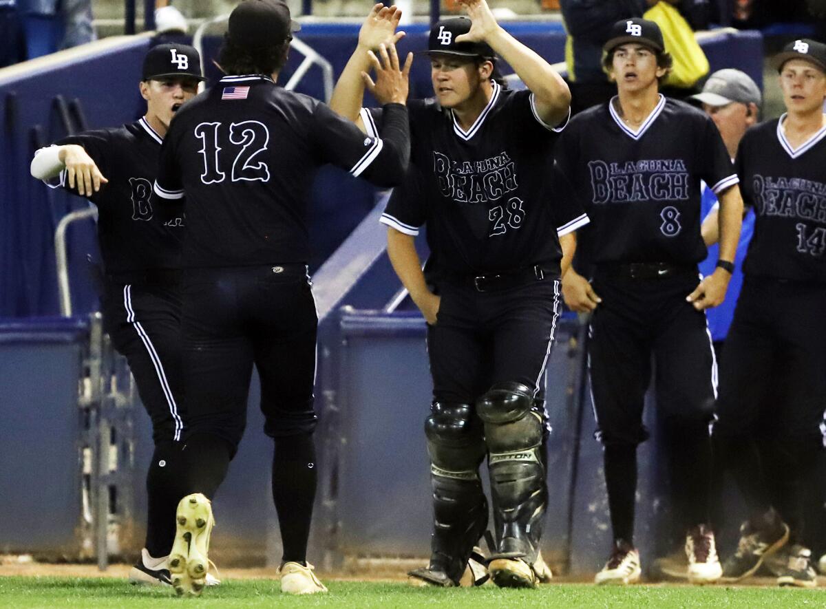 Laguna Beach's Dylan Yencho (12) gets high-fives after striking out a batter in extra innings against Glendora.