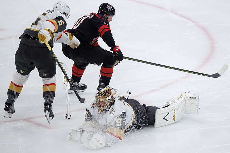 Vegas Golden Knights' goaltender Carter Hart (79) loses his stick as he dives for the puck past teammate Jeremy Lauzon (5) and Carolina Hurricanes' Eric Robinson, top right, during the third period of Game 5 of the NHL hockey Stanley Cup Final series in Raleigh, N.C., Thursday, June 11, 2026. (AP Photo/Ben McKeown)