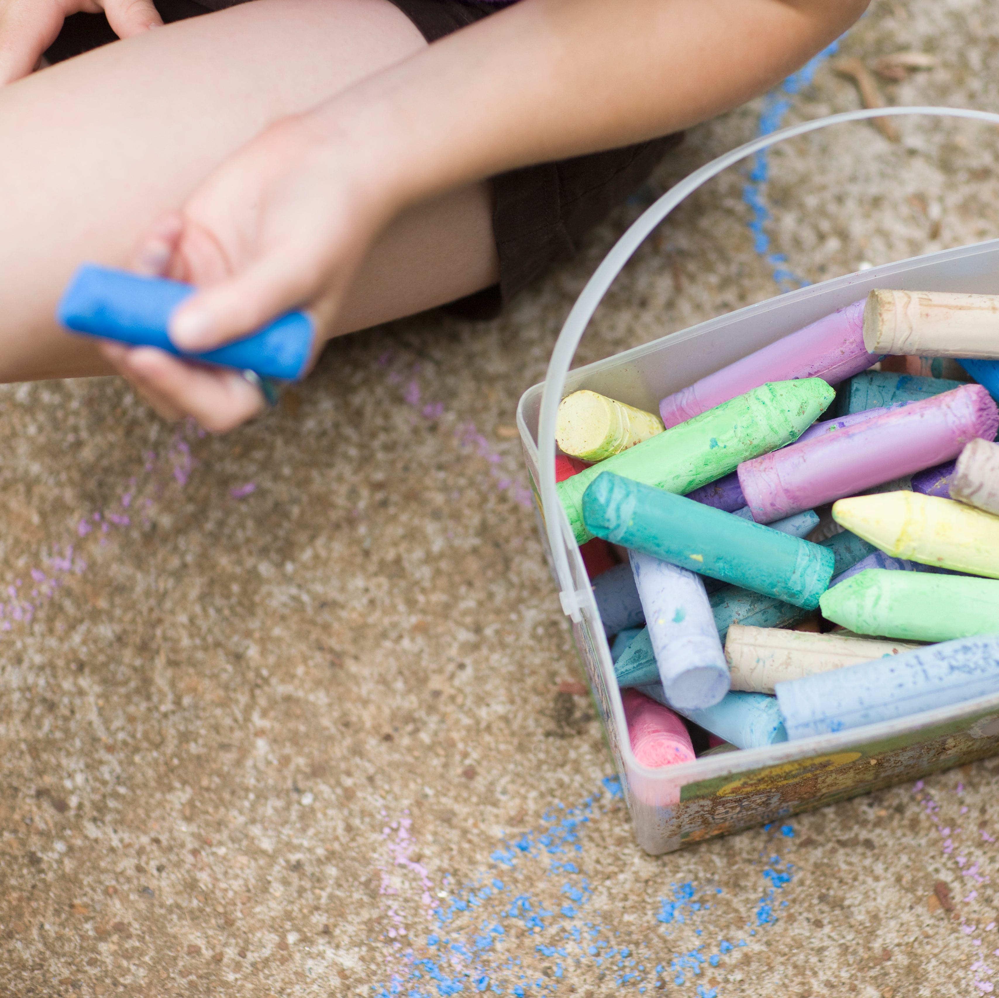 Caucasian girl drawing on sidewalk with chalk