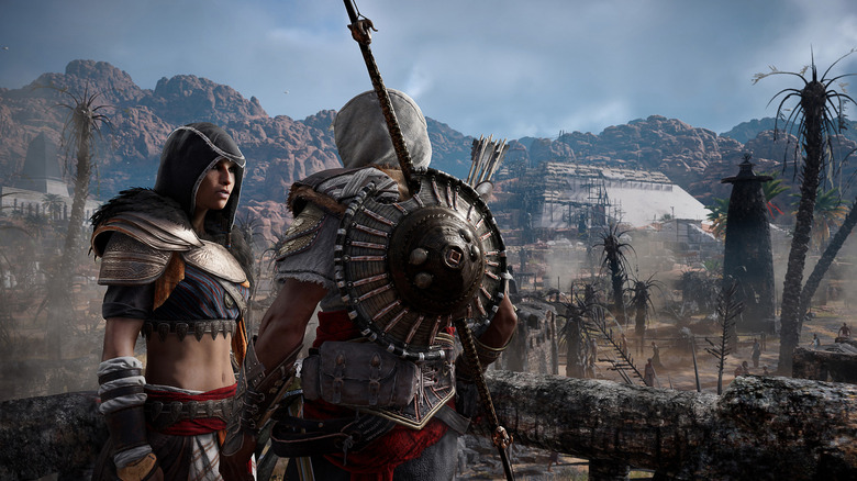 Aya and Bayek look at each other by a wooden railing in Assassin's Creed Origins