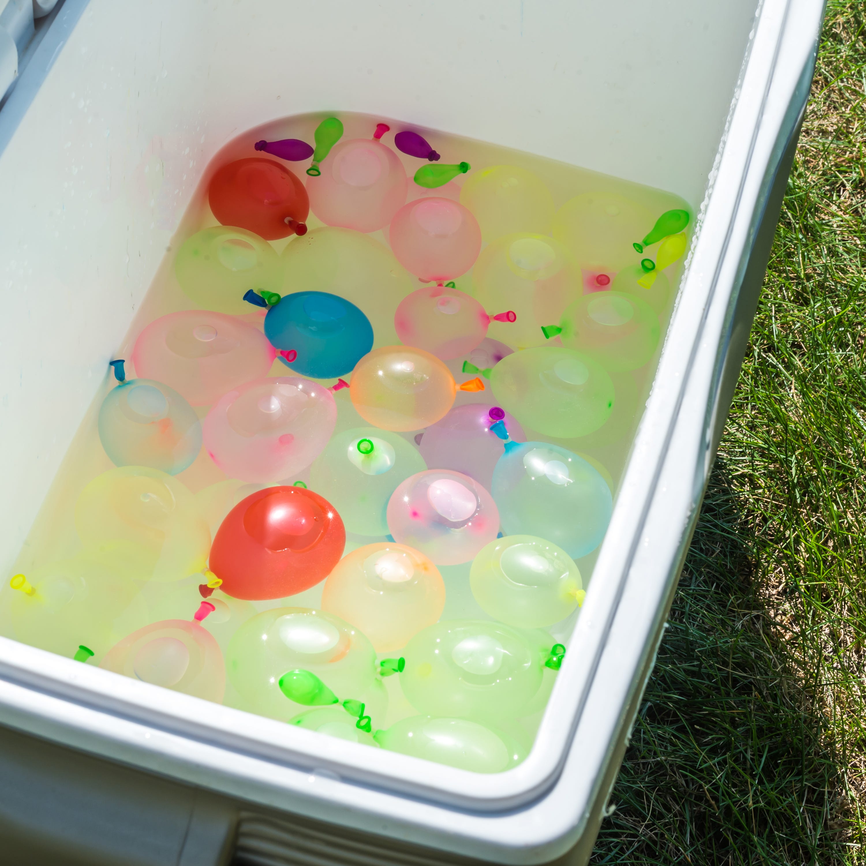 Colorful water balloons in a water cooler at an outdoor summer party