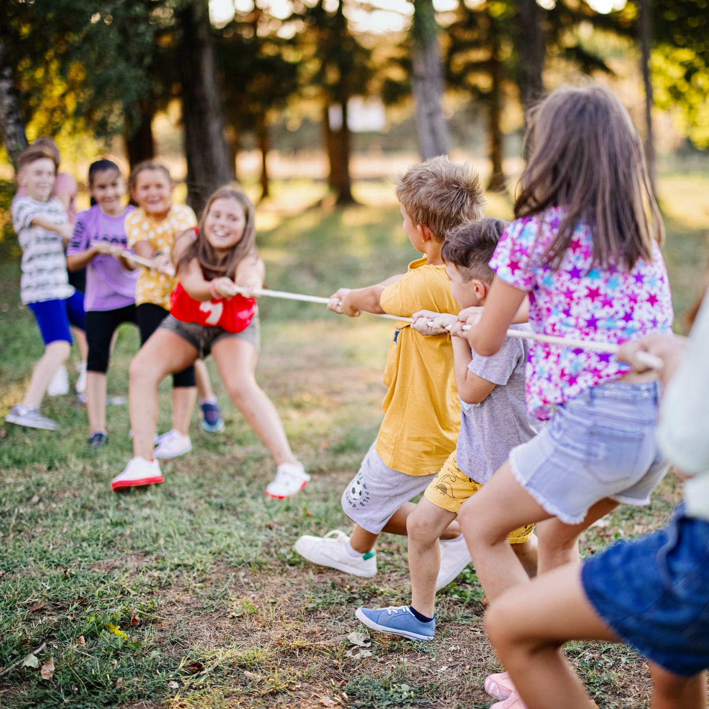 School children playing tug of war with rope in a summer camp