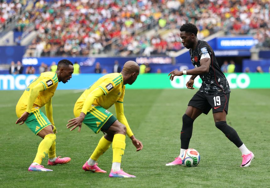 Canada's Alphonso Davies is defended by two South African players in the second half.