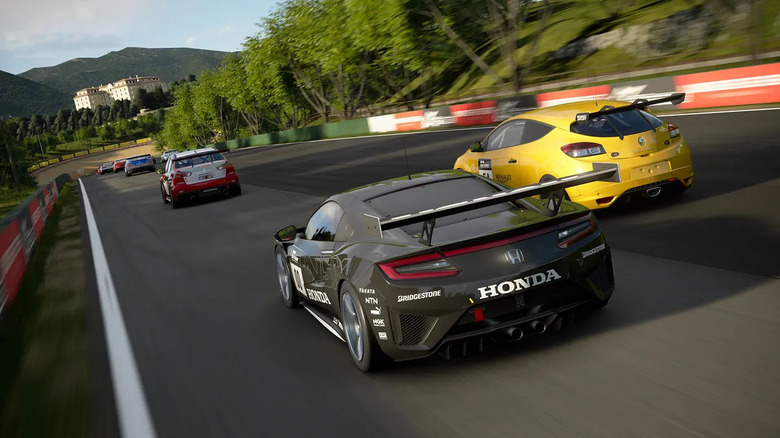 A group of cars race down a track in a forest in Gran Turismo 7