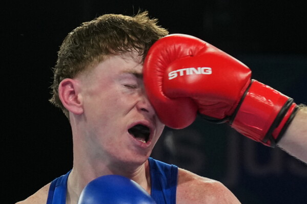 New Zealand's Finbar O'Sullivan, in blue, takes punch from Scotland's Nicholas Devlin during the Men's 80Kg round 32 boxing bout at the Commonwealth Games in Glasgow, Scotland, Saturday, July 25, 2026. (AP Photo/Eranga Jayawardena)