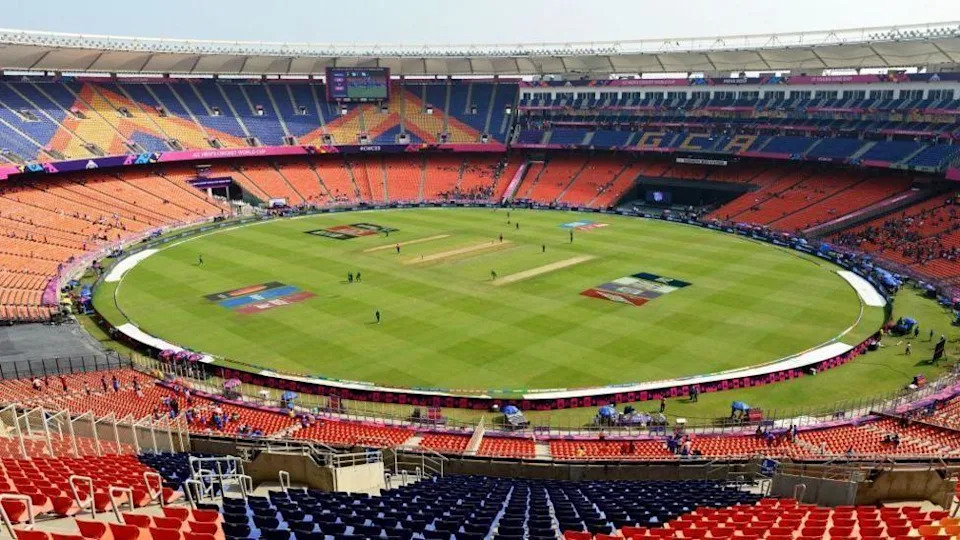 A large stadium with a cricket game taking place on it