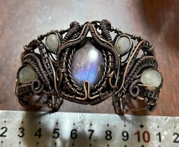 "A biomechanical cyber-relic. Woven copper wires encapsulating Labradorite and Moonstone, mimicking neural cyberware."