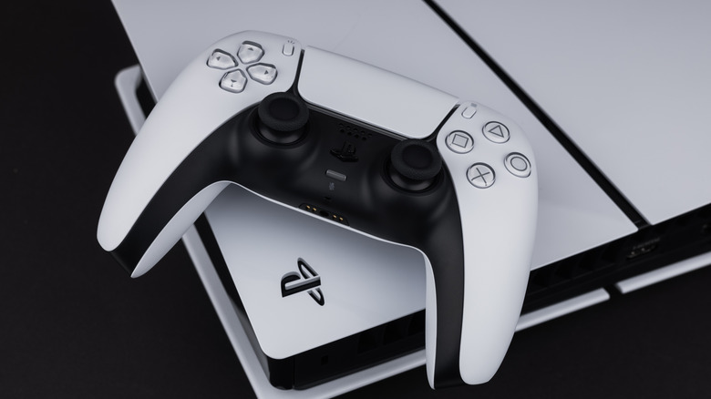 White PlayStation 5 controller and console on black surface