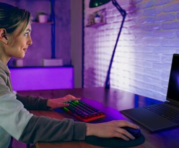 A woman smiles as she uses her Alienware 15 laptop