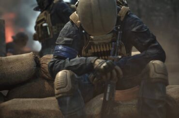 Wardogs solider sitting with hands clasped around rifle