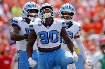 UNC's Xavier Lewis reacts after making a sack against Clemson while teammates celebrate with him.